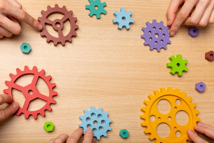 A number of people’s hands bringing cogs together in the middle of the picture.