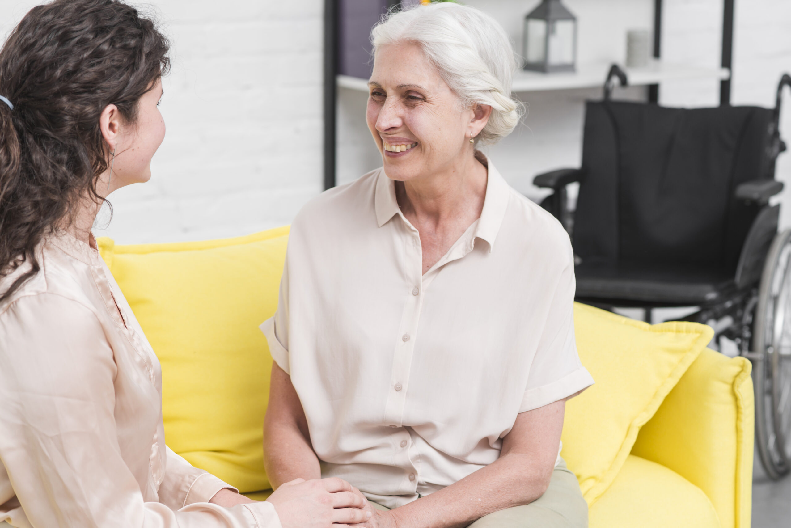 Older adult woman talking to adult woman on sofa